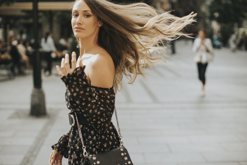 Young long hair brunette woman walking on the street/ envato